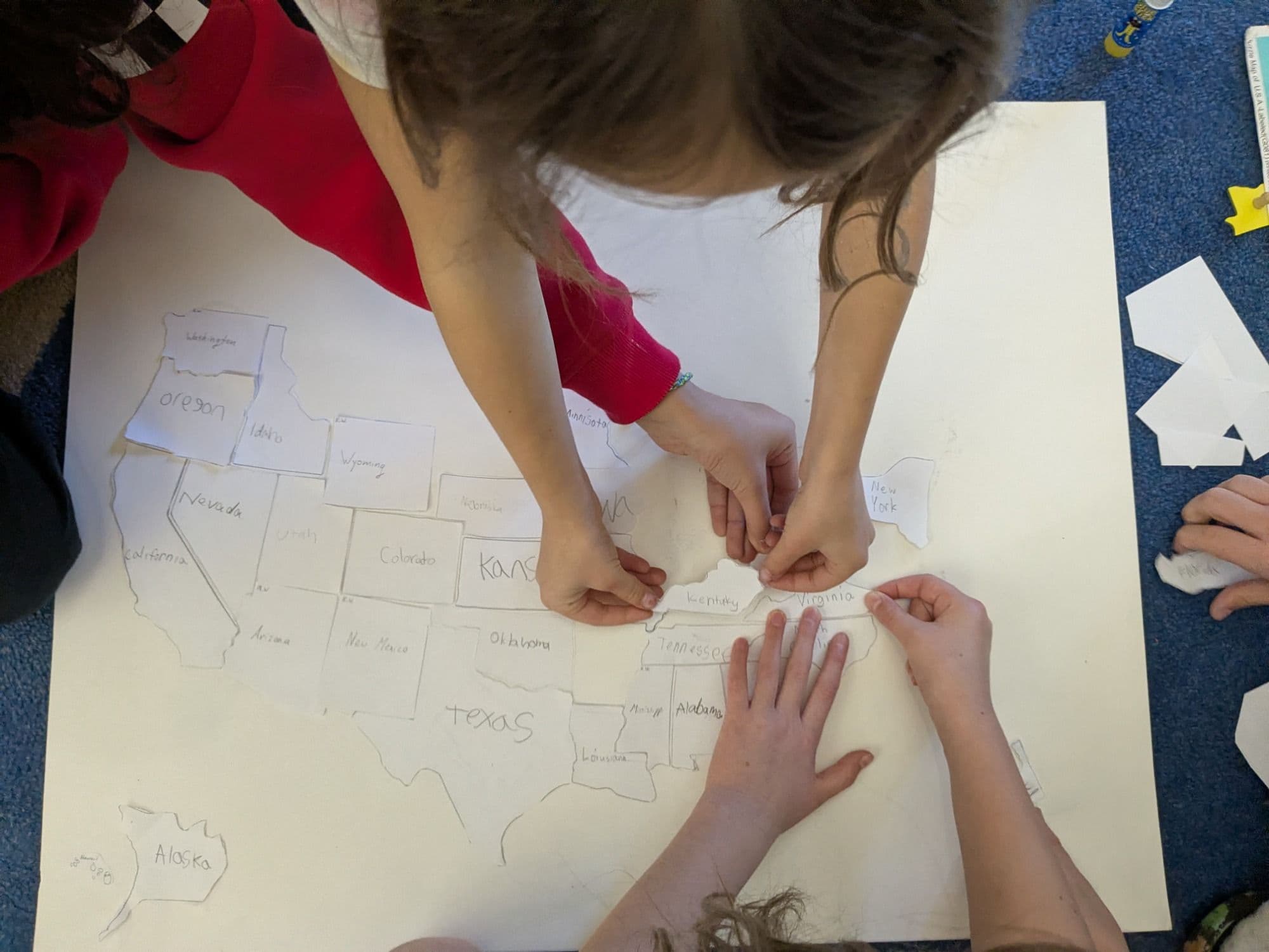 Students assembling a hand-drawn map of the United States on the classroom floor