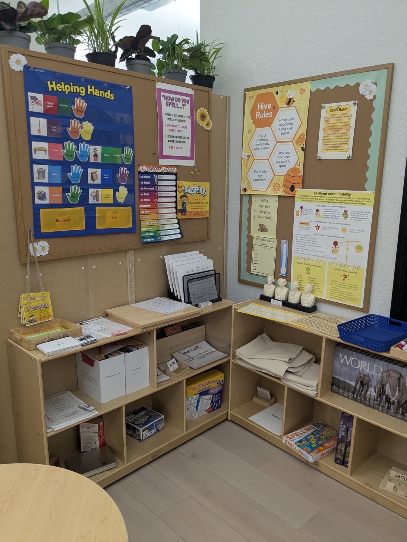 A Meadow View classroom wall with a Helping Hands job chart, a virtue chart and the Hive Rules board above the materials shelves