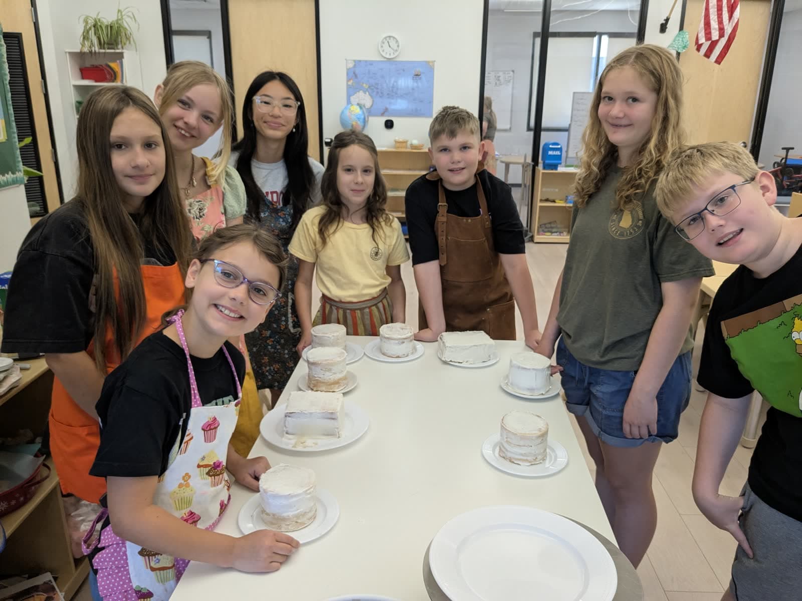Students around a table with the cakes they decorated