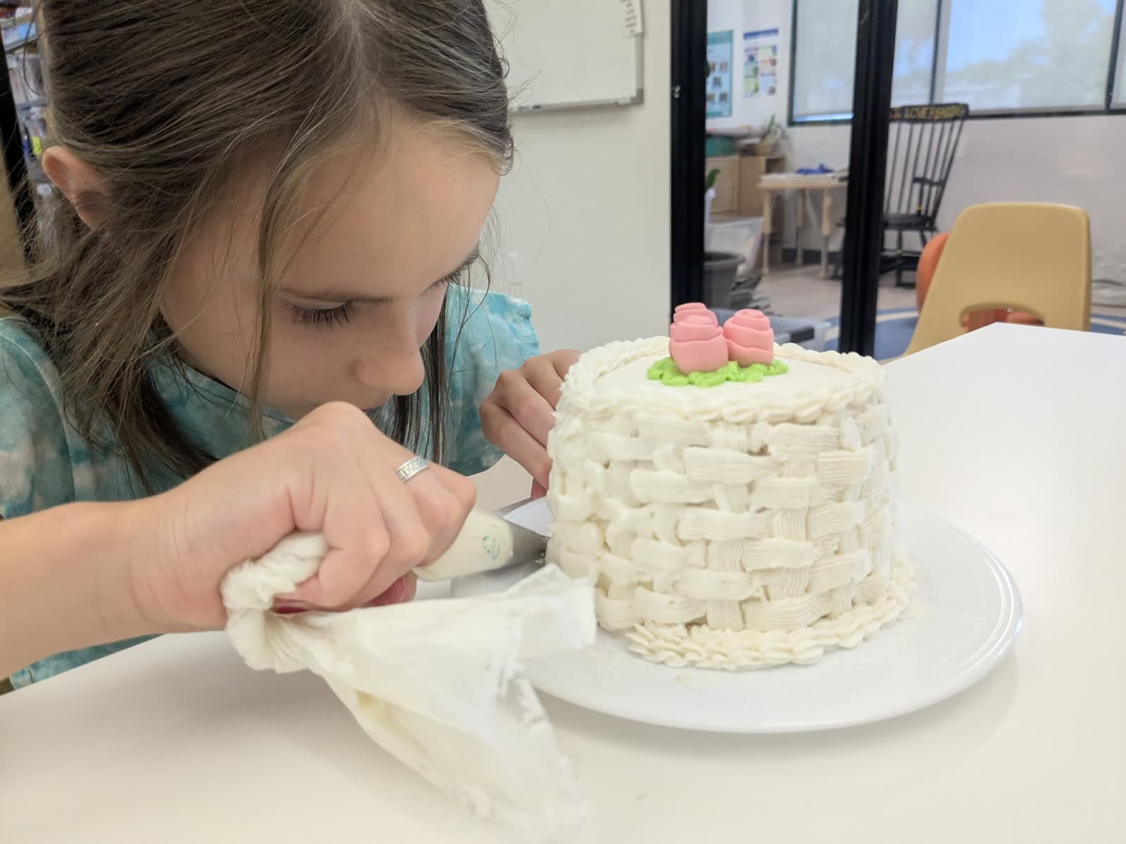 A student piping icing onto a cake in class