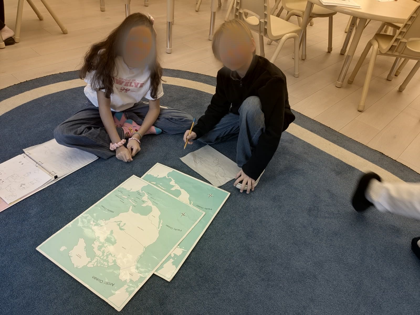 Two students working together on large floor maps in a Meadow View Learning classroom