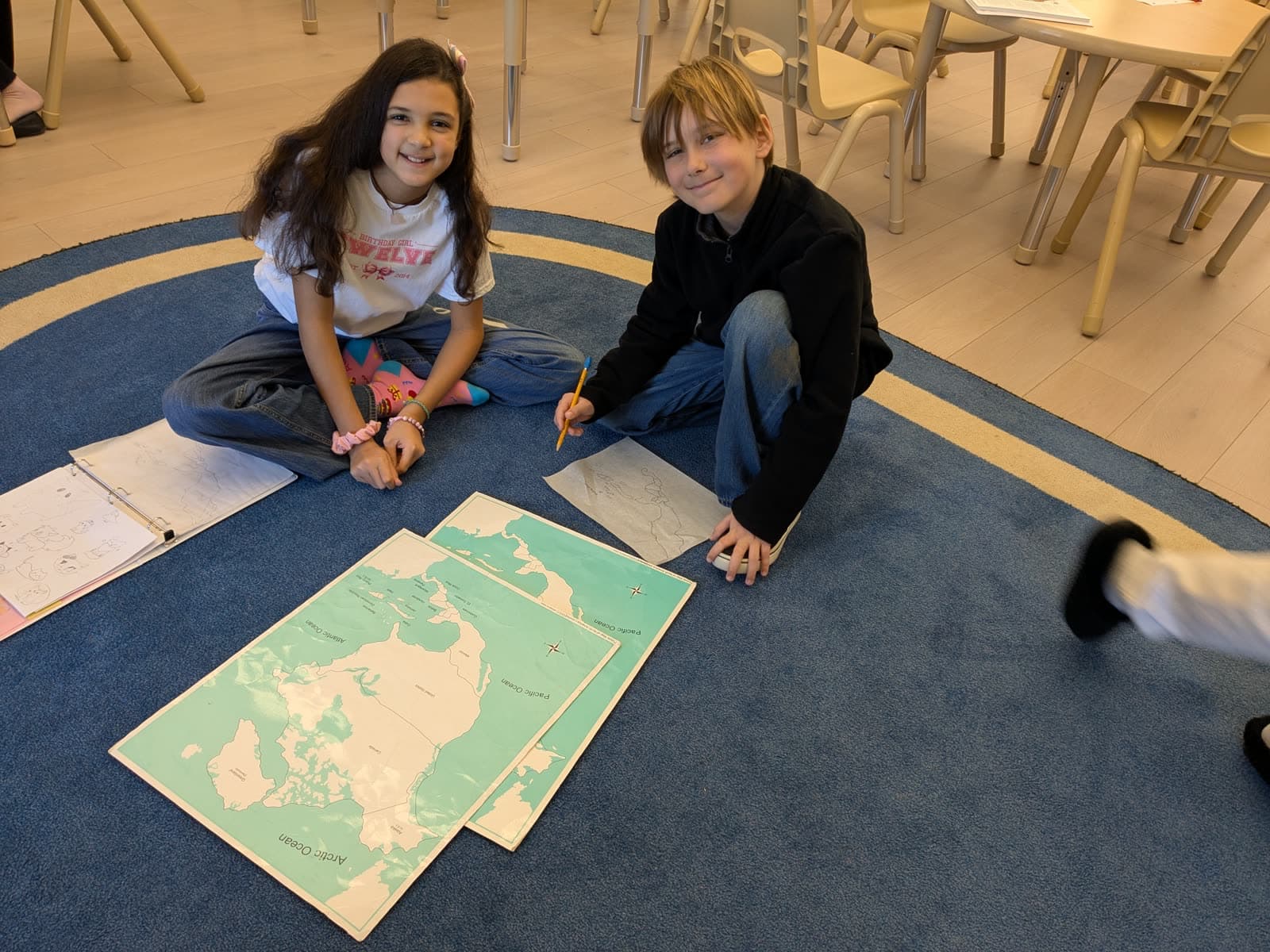 Two students working together on large floor maps in a Meadow View classroom