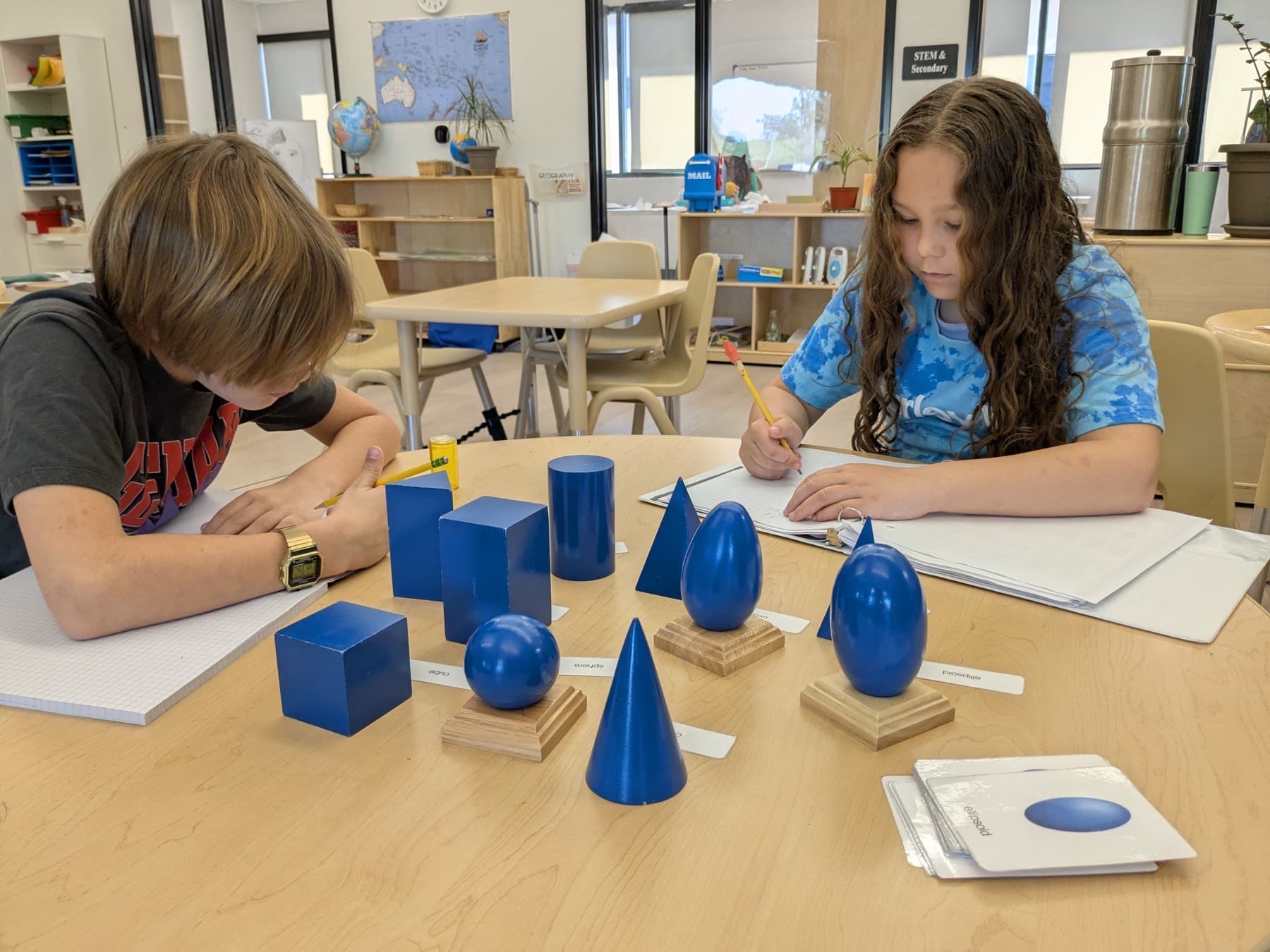 Two Meadow View students working with geometric solids at a classroom table